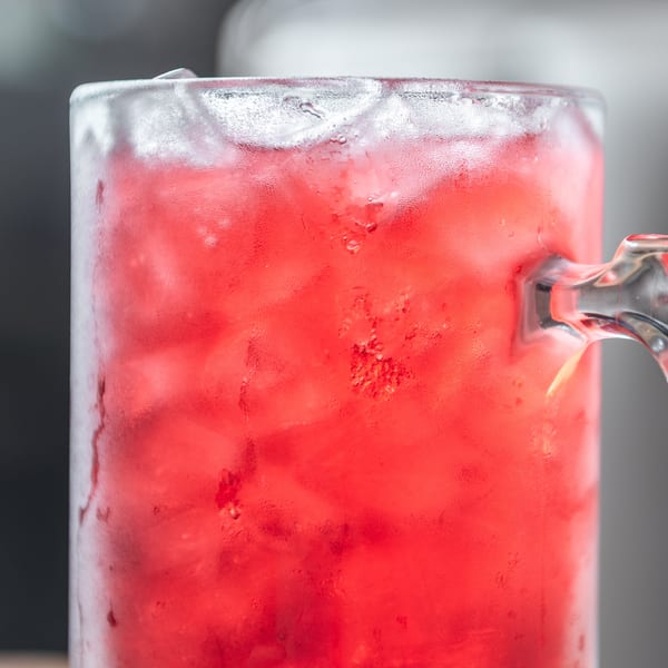 Frosty mug filled with a vibrant red drink and ice, covered in condensation.