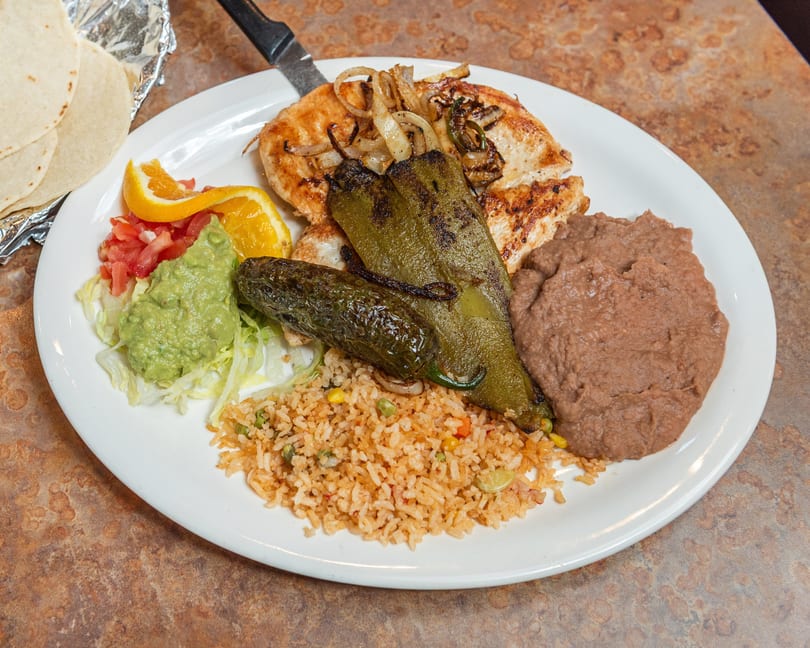 Grilled chicken with roasted peppers, rice, refried beans, guacamole, pico de gallo, and tortillas.