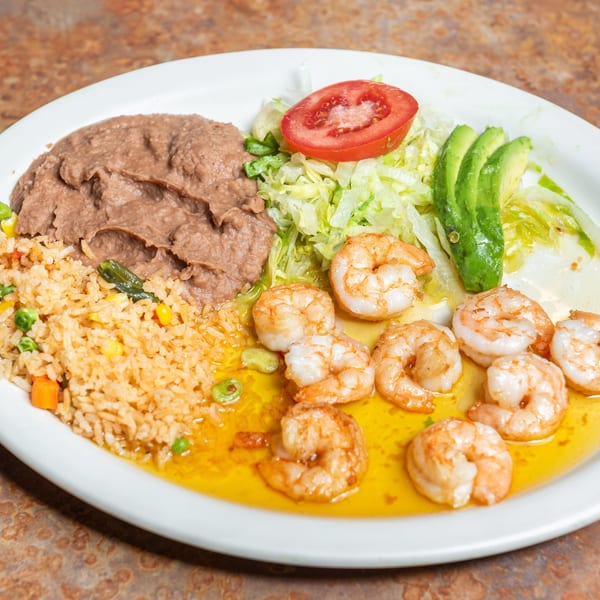 Delicious shrimp dish with rice, refried beans, lettuce, tomato, and avocado slices.